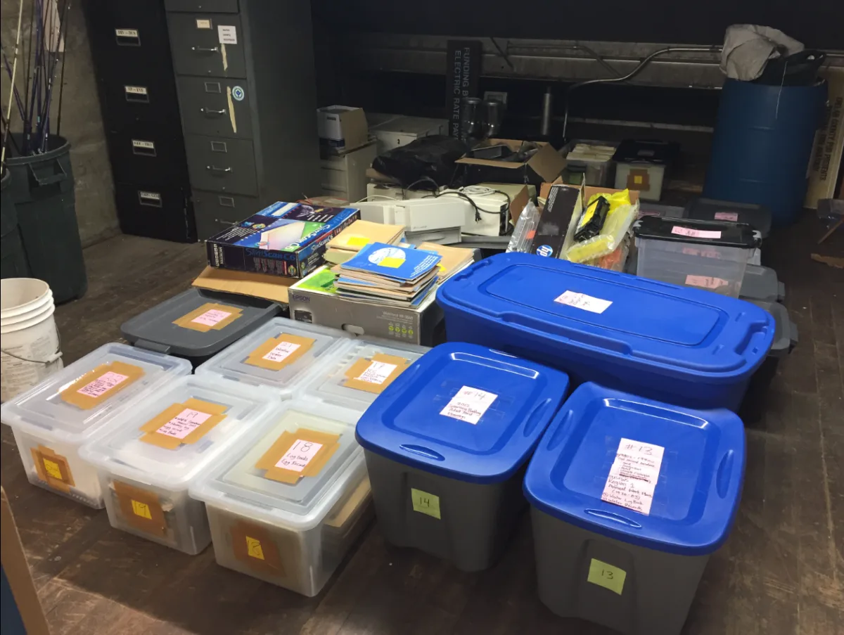 Papieren dossiers en documenten opgeslagen in gelabelde plastic opbergbakken en archiefkasten in een opslagruimte